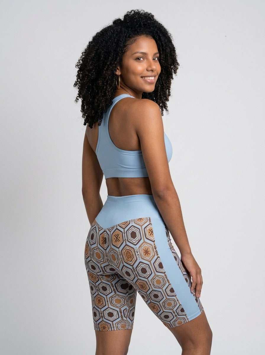 AnanseNova™ Biker Shorts in Igwe Blue styled with a matching sports bra, over-the-shoulder back view — SunBorn
