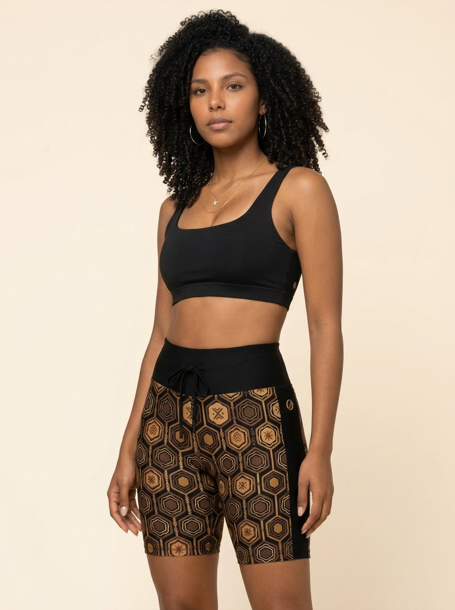 AnanseNova™ Biker Shorts in Oji Black styled with a black sports bra, studio portrait — SunBorn