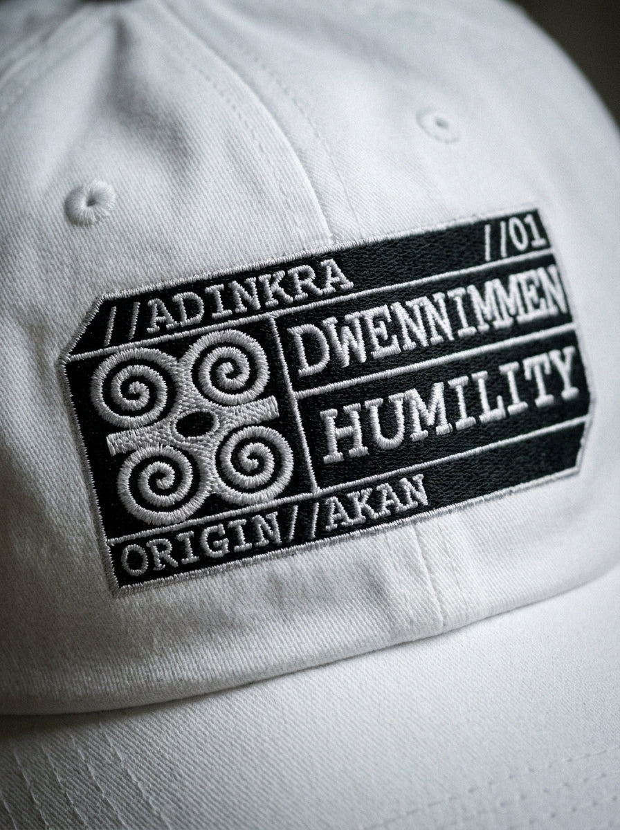 Adinkra Humility Dad Hat in Ocha White — macro detail of embroidered Dwennimmen glyph badge