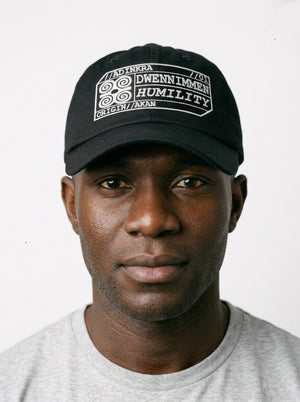Adinkra Humility Dad Hat in Oji Black — worn front view, embroidered Dwennimmen badge