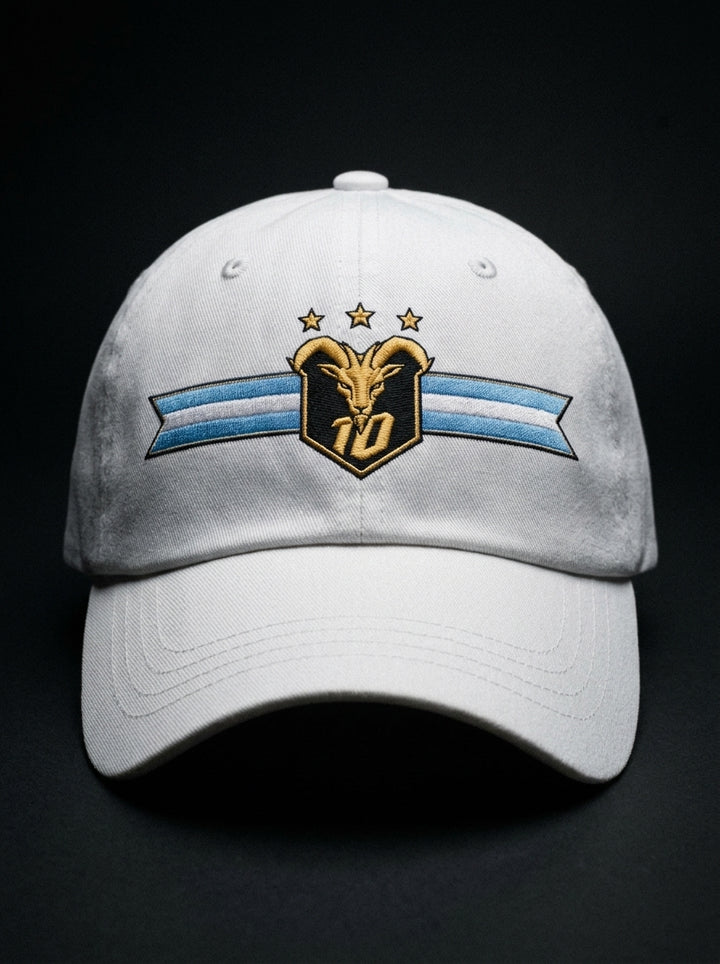 GOAT Celeste Dad Hat in Ocha White, front view — gold goat crest with N°10 and three stars on an Albiceleste ribbon.