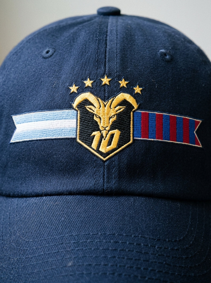 GOAT Fusión dad hat in Anụnụ Blue — macro detail of the unlimited-colour embroidered crest, split Argentina + Barça ribbon