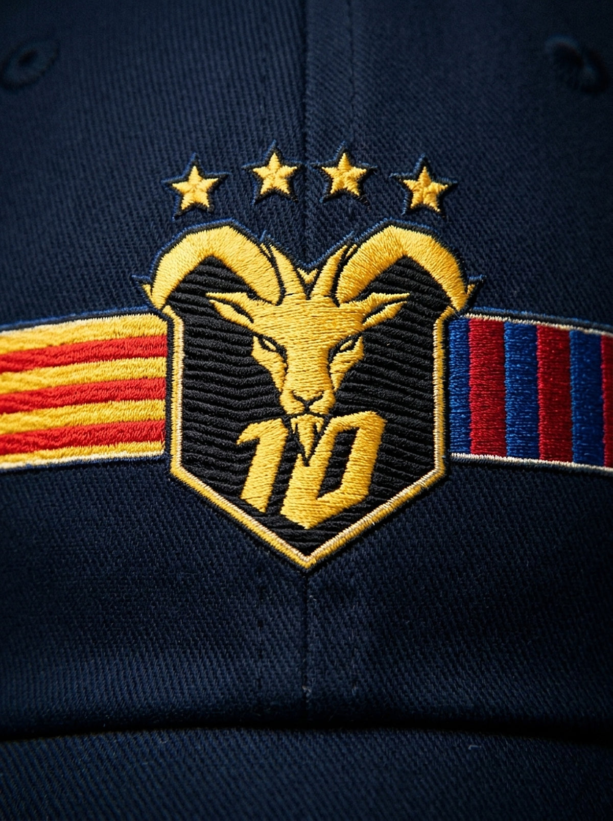 Close-up of the unlimited-colour embroidery on the GOAT Catalan dad hat in Anụnụ Blue — gold goat, No. 10 and the split Senyera and blaugrana banner in full-tone thread.