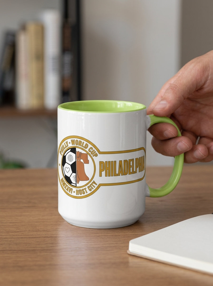 Liberty Protocol Philly '26 Mug — White Ceramic with Lime interior, held by the handle on a wood desk with a notebook
