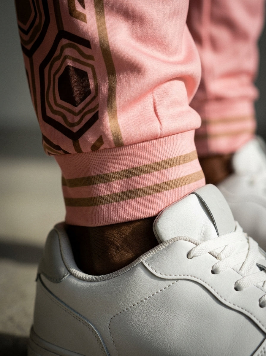 AnanseNova™ Men's Joggers in Eze Pink, close-up of the bronze-striped ribbed ankle cuff and hexagon panel detail. SunBorn