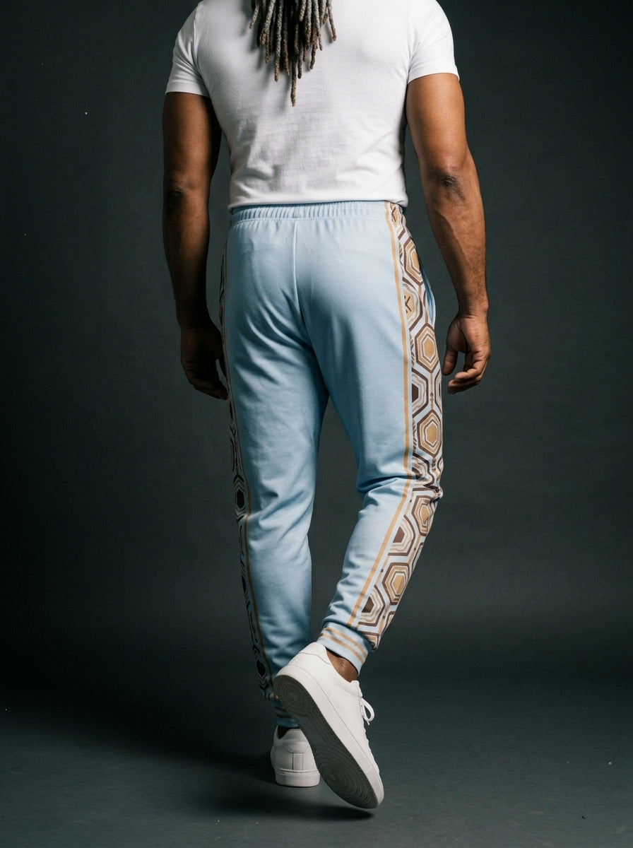 AnanseNova™ Men's Joggers in Igwe Blue, back view on model — hexagon side panels running waist to cuff, slim athletic fit. SunBorn