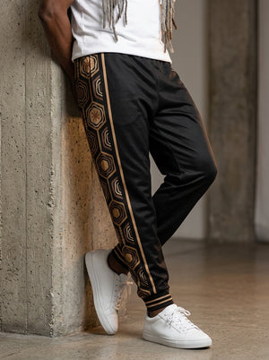 AnanseNova™ Men's Joggers in Oji Black, front view on model — AnanseNova™ hexagon side-panel stripe edged in bronze pinstripes, striped ribbed ankle cuffs. SunBorn
