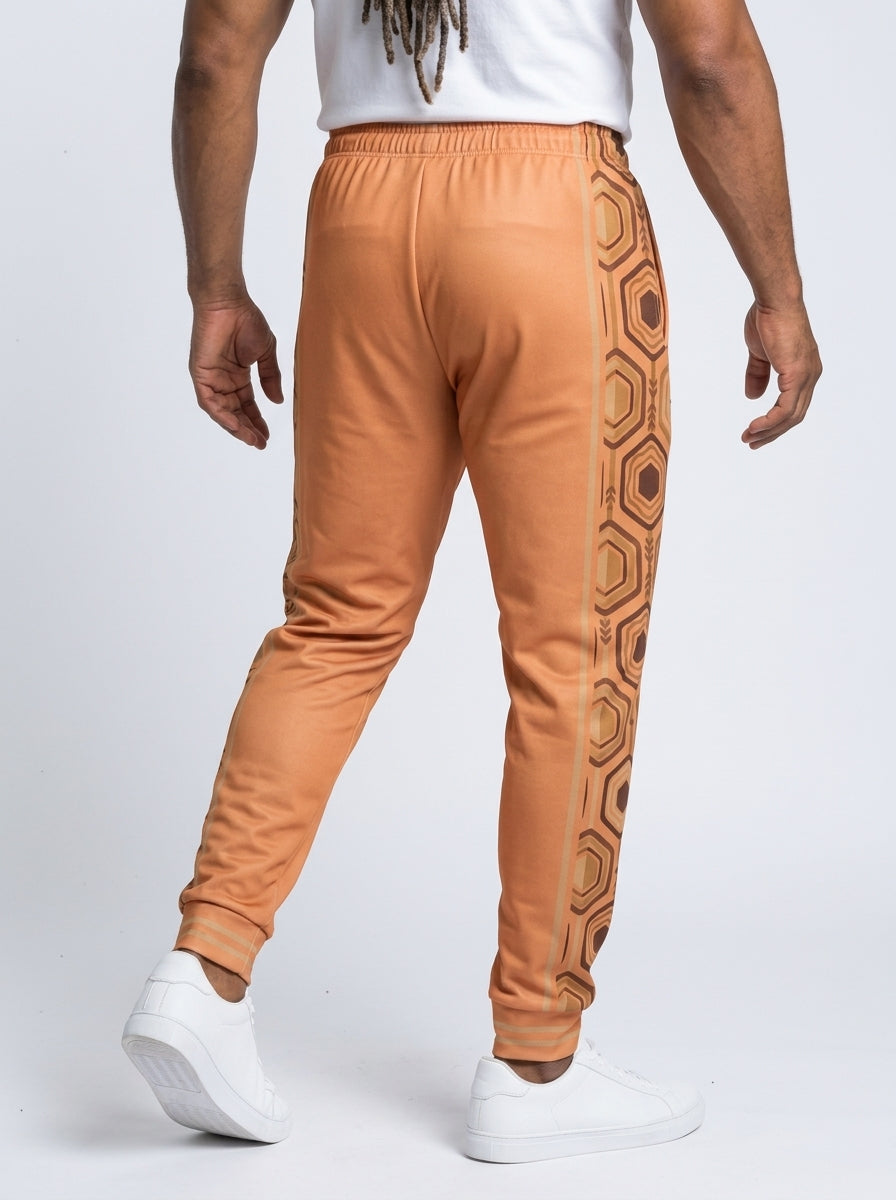AnanseNova™ Men's Joggers in Sango Orange, back view on model — hexagon side panels running waist to cuff, slim athletic fit. SunBorn