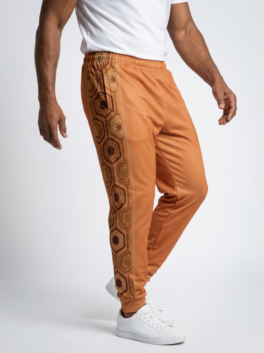 AnanseNova™ Men's Joggers in Sango Orange, three-quarter right view on model — slim tapered leg, striped ribbed ankle cuffs. SunBorn