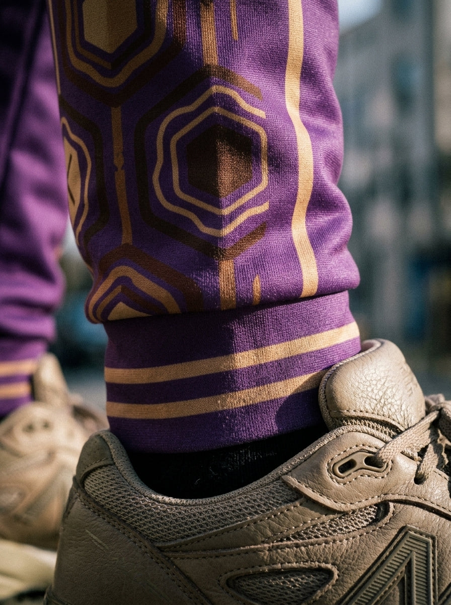 AnanseNova™ Men's Joggers in Ugo Purple, close-up of the bronze-striped ribbed ankle cuff and hexagon panel detail. SunBorn