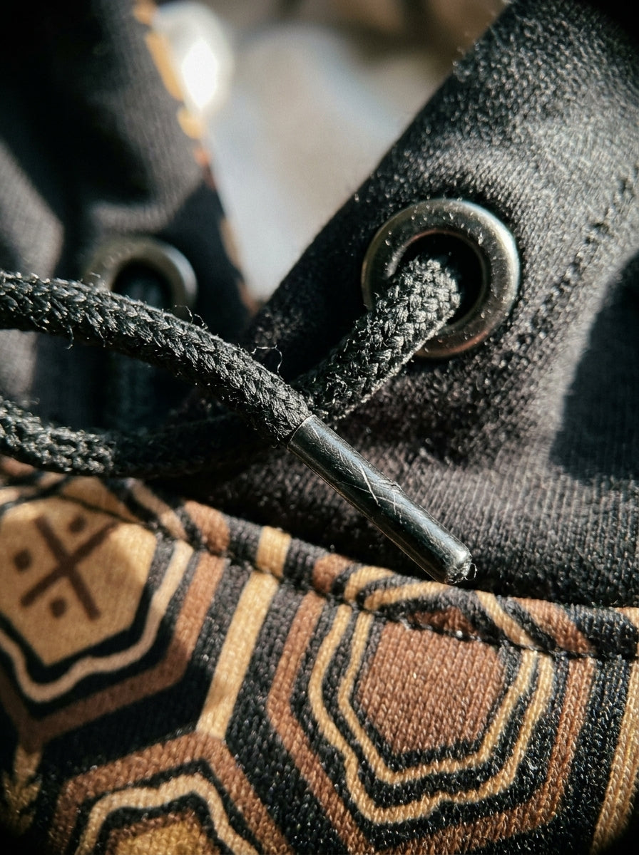 AnanseNova™ // Statement Hoodie in Oji Black — macro detail — SunBorn