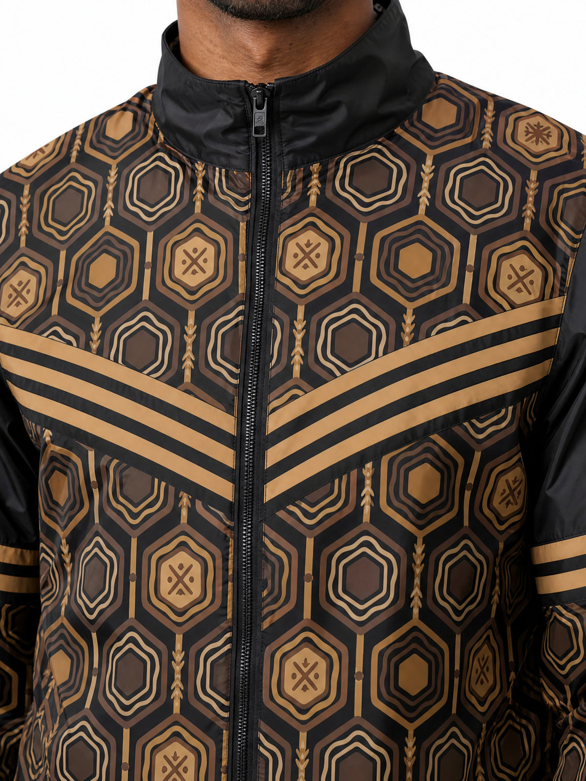 AnanseNova™ Men's Windbreaker in Oji Black — close-up of the bronze chevron, zipper and hexagon print on the MframaShell™ water-resistant shell