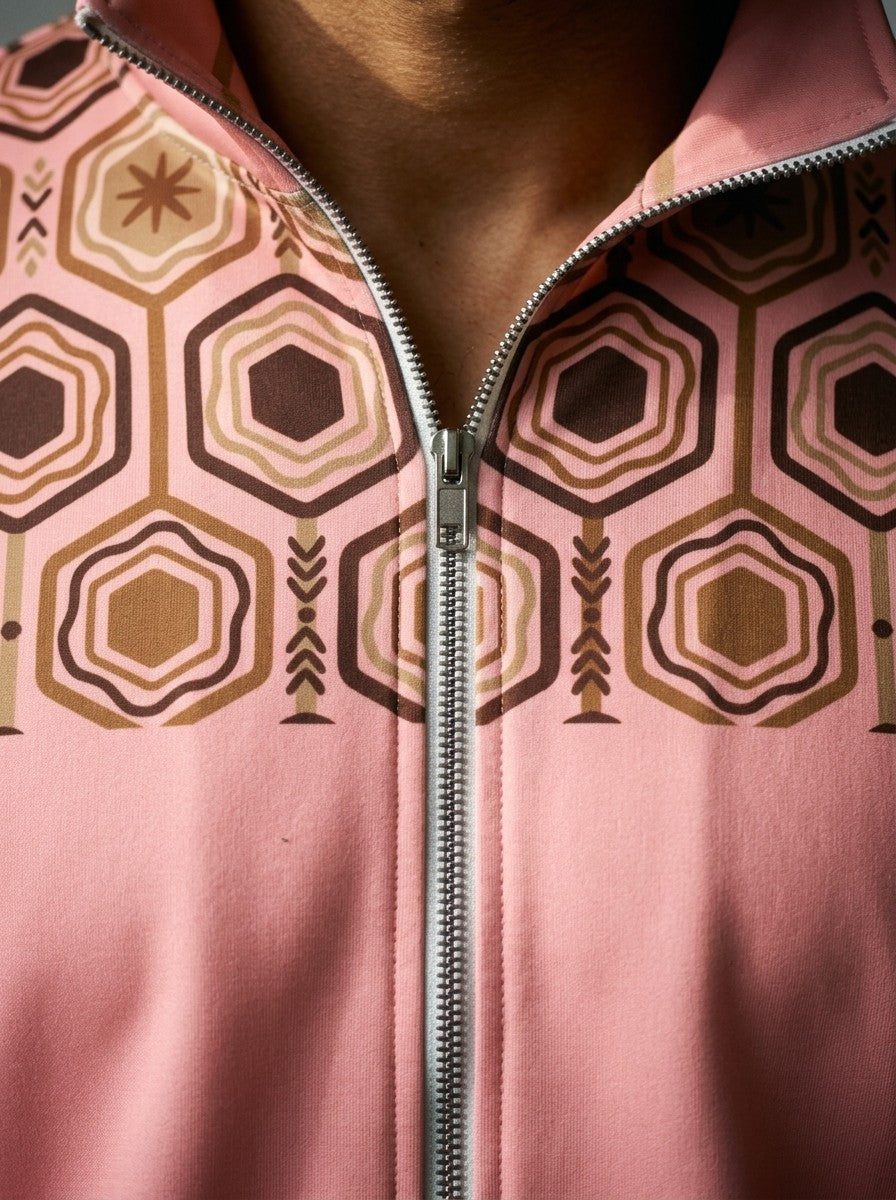 Close-up of the AnanseNova™ Track Jacket in Eze Pink: open collar, zip and the brown and gold hexagon print yoke