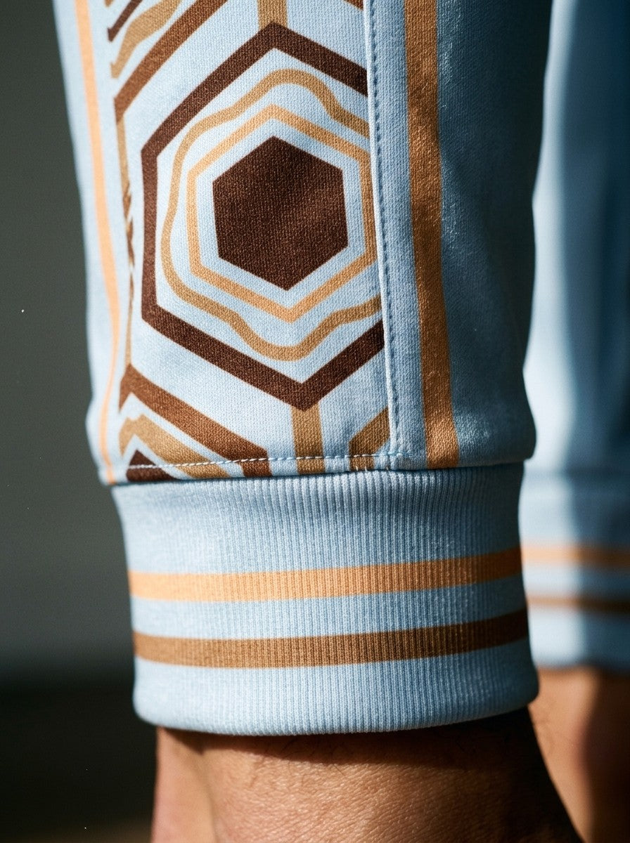 Close-up of the AnanseNova™ Joggers cuff in Igwe Blue: striped ribbed cuff and the brown and gold hexagon side stripe