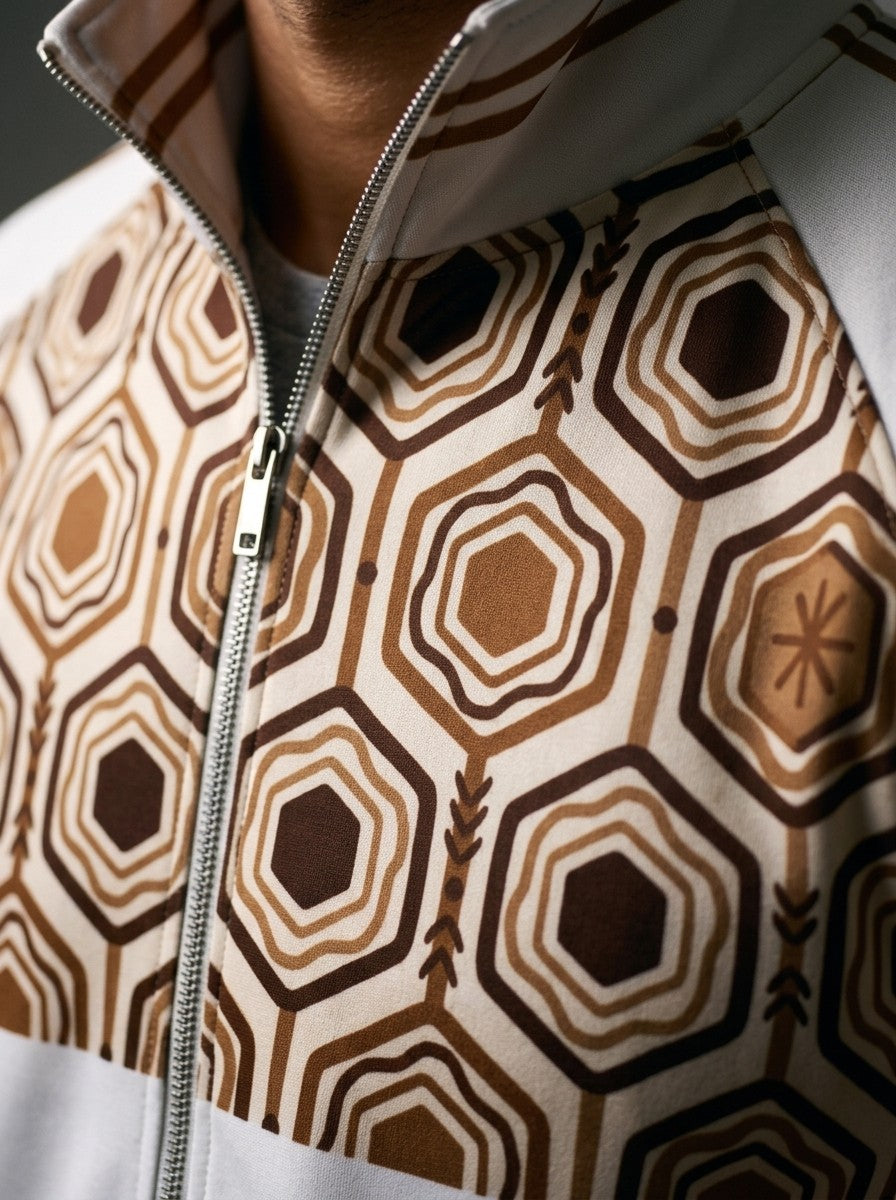 Close-up of the AnanseNova™ Track Jacket in Ocha White: striped collar, zip and the brown and gold hexagon print yoke