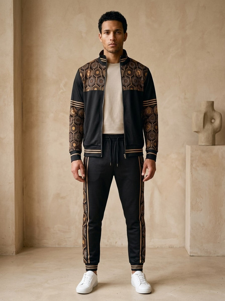 AnanseNova™ Track Jacket + Joggers Set in Oji Black, front view on model: black track jacket with brown and gold hexagon print yoke and sleeves, gold sleeve stripes, matching black joggers with hex side stripes