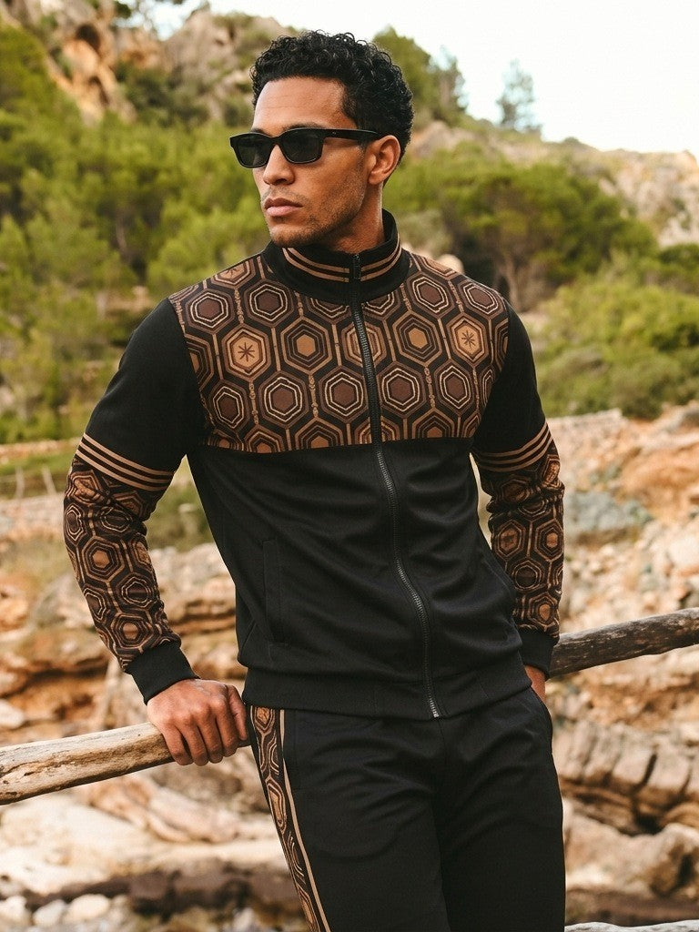 Man in sunglasses leaning on a wooden rail on a rocky hillside, wearing the AnanseNova™ Track Jacket + Joggers Set in Oji Black