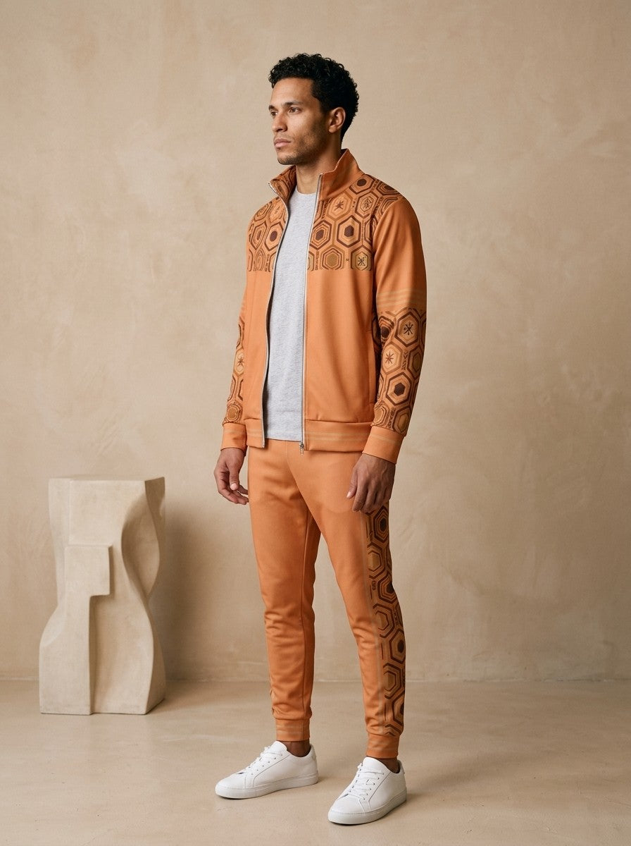 AnanseNova™ Track Jacket + Joggers Set in Sango Orange, three-quarter left view on model showing the printed sleeve and jogger side panel