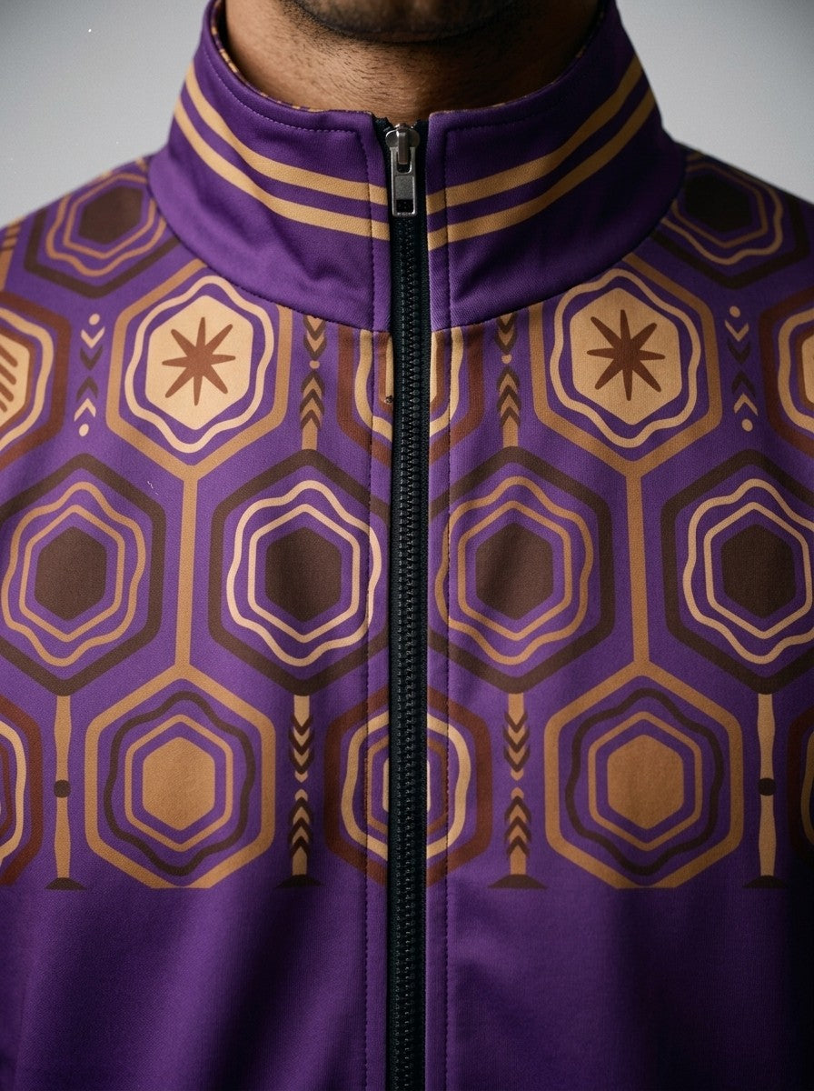 Close-up of the AnanseNova™ Track Jacket in Ugo Purple: striped collar, black zip and the brown and gold hexagon print yoke