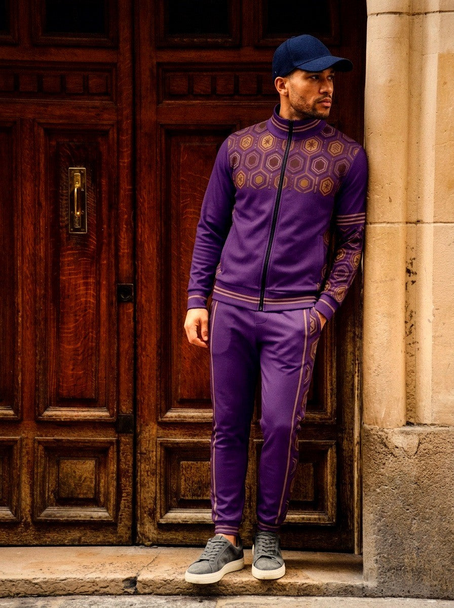 AnanseNova™ Track Jacket + Joggers Set in Ugo Purple, lifestyle shot: model in a navy cap leaning against a stone doorway beside carved wooden doors