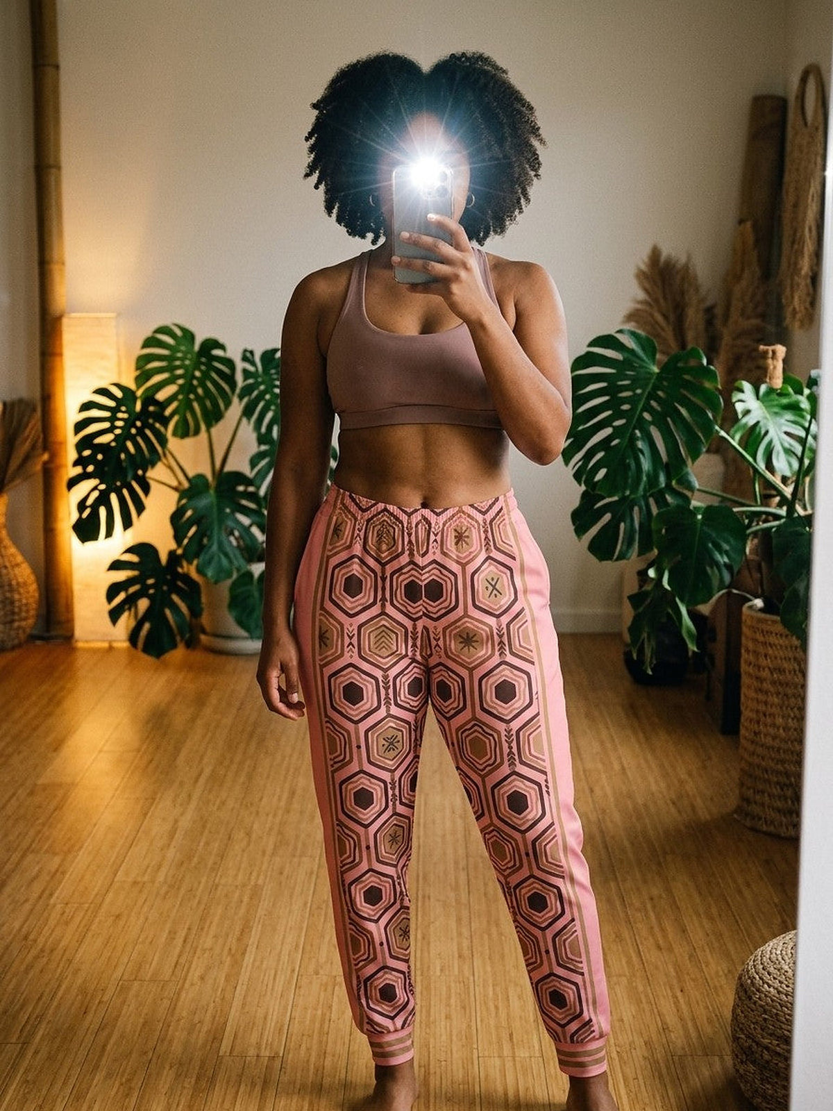 Mirror selfie in a plant-filled room wearing AnanseNova™ Women's Joggers in Adaeze Pink with a mauve sports bra