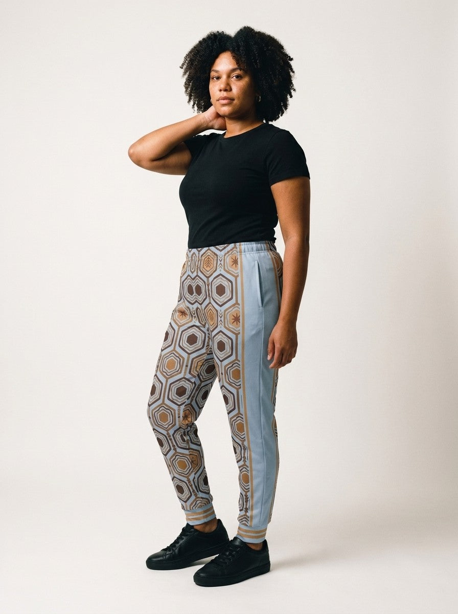 Three-quarter view of AnanseNova™ Women's Joggers in Igwe Blue on model, side panel, pocket and bronze side stripe, styled with a black tee