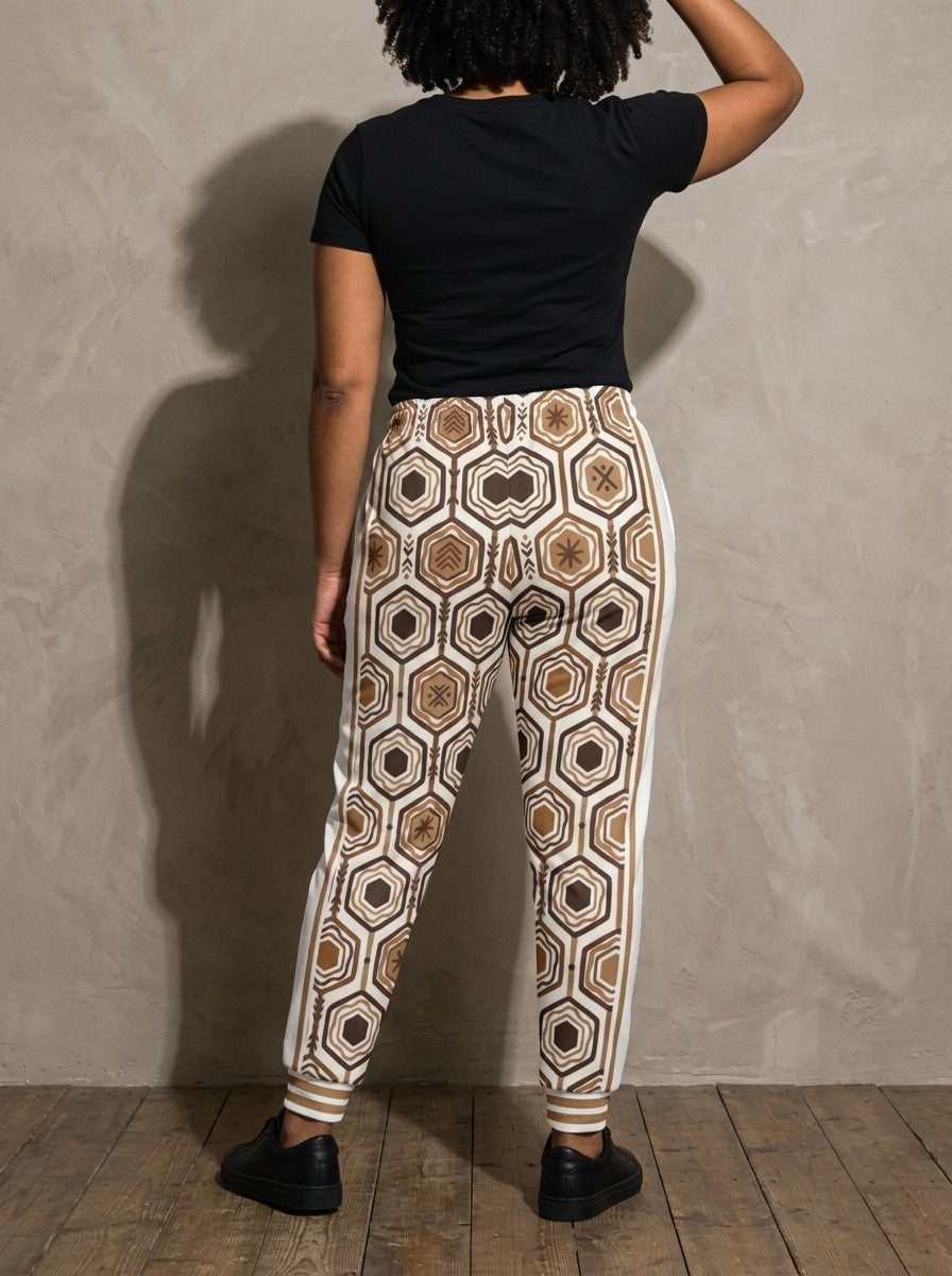 Back view of AnanseNova™ Women's Joggers in Ocha White on model, hexagon print continuing across the seat and legs, styled with a black tee
