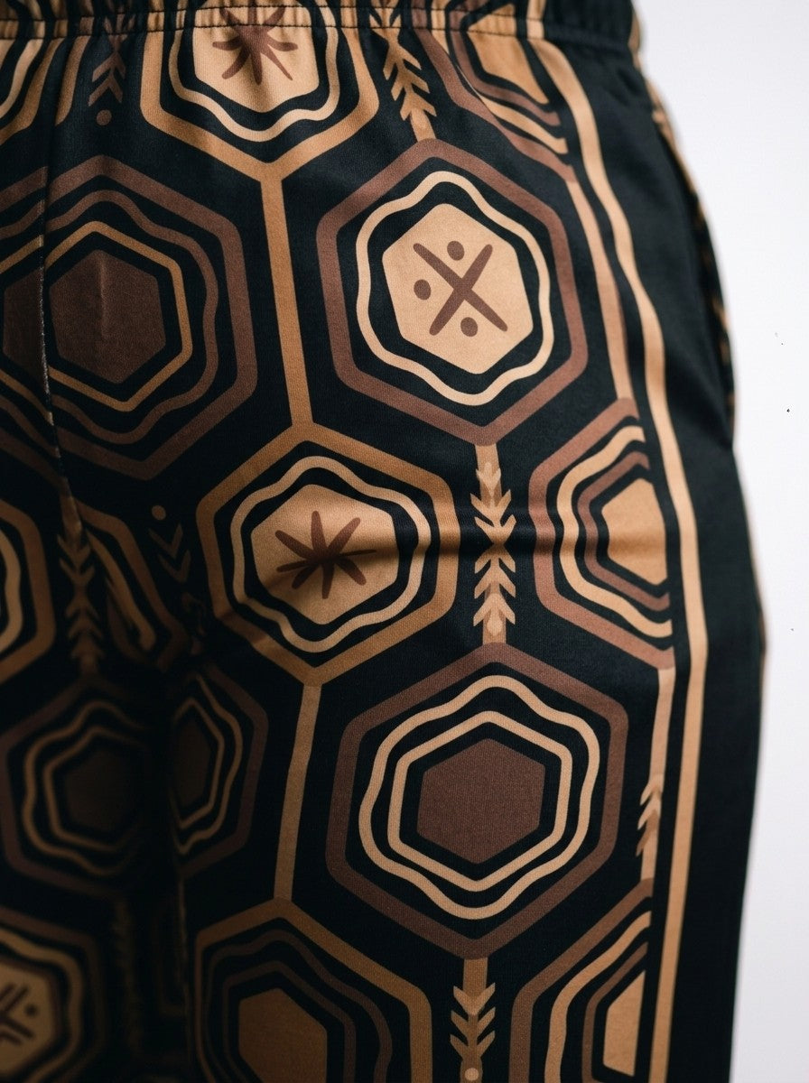 Close-up of the sublimation-printed AnanseNova™ hexagon pattern and bronze side stripe on Oji Black women's joggers