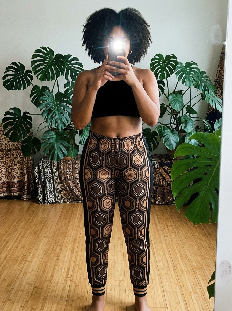 Mirror selfie in a plant-filled sunlit room wearing AnanseNova™ Women's Joggers in Oji Black with a black crop top