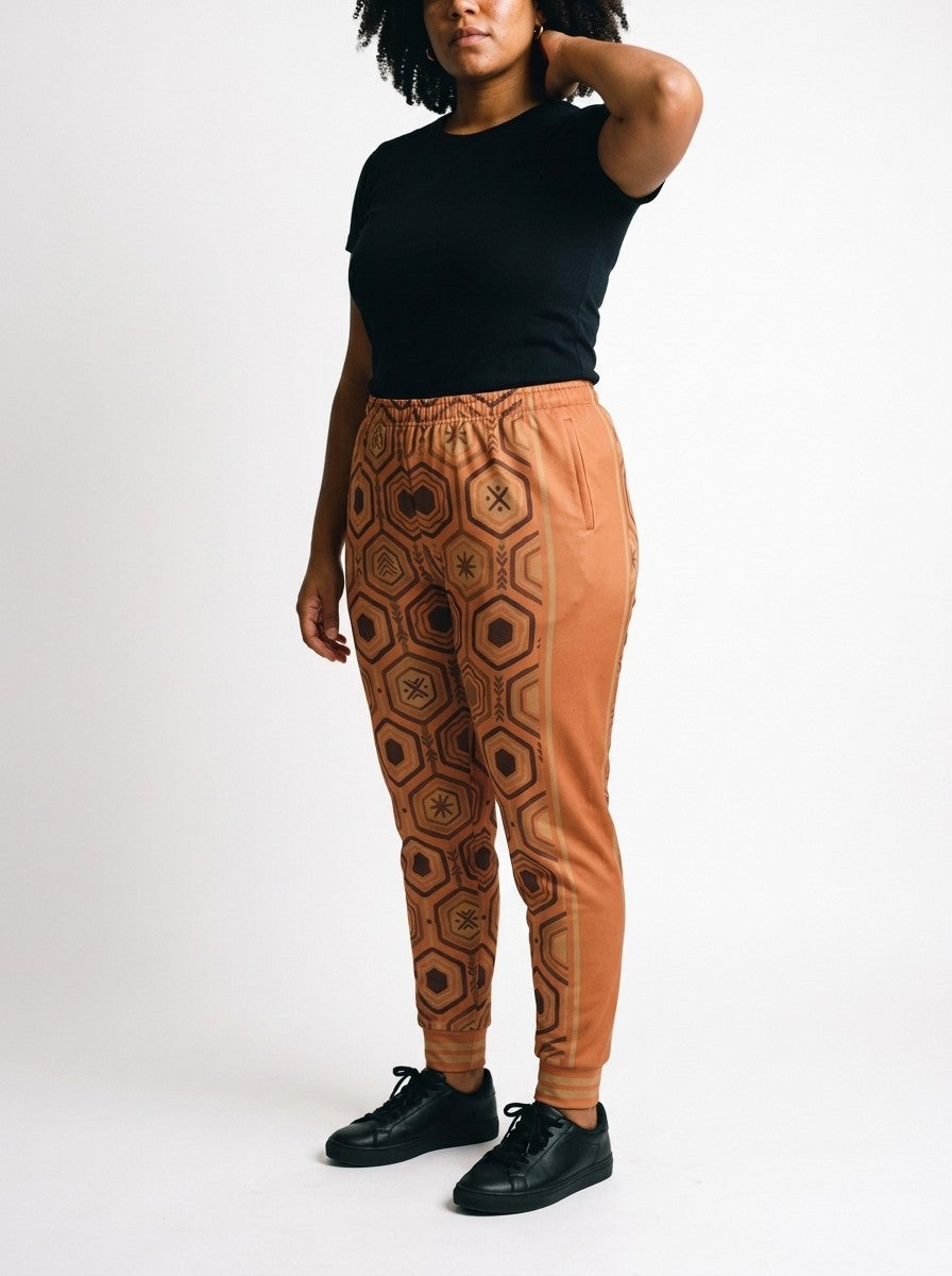 Three-quarter view of AnanseNova™ Women's Joggers in Sango Orange on model, orange side panel, pocket and bronze side stripes