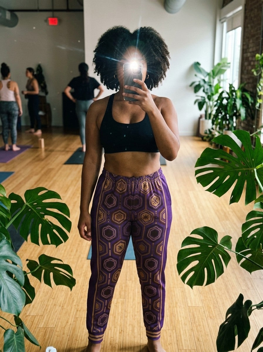 Mirror selfie in a plant-filled yoga studio wearing AnanseNova™ Women's Joggers in Ugo Purple with a black sports bra