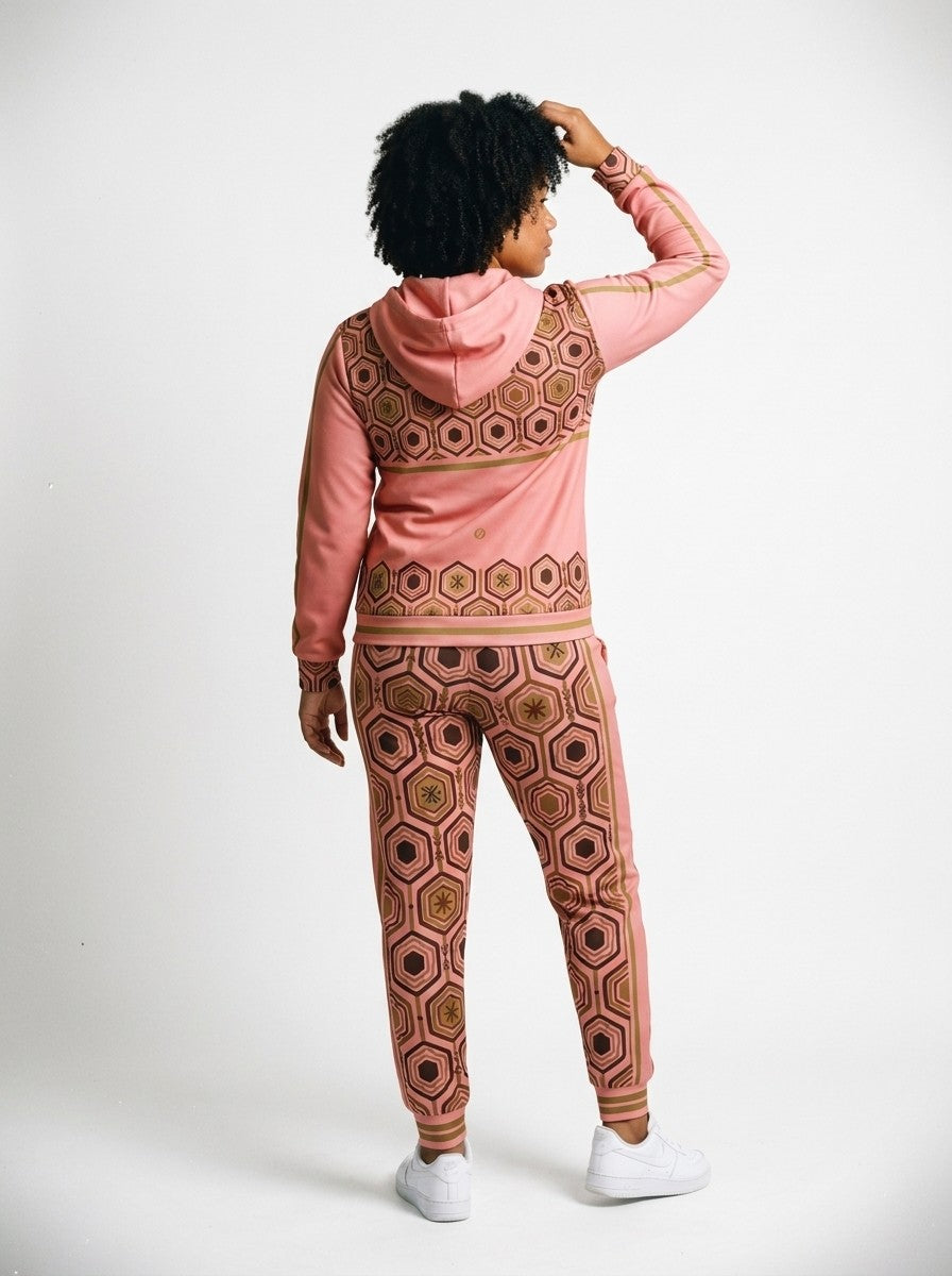 Back view of the AnanseNova™ women's Zip Hoodie + Joggers set in Adaeze Pink on model, hexagon back yoke, bronze sleeve stripes and printed joggers | SunBorn