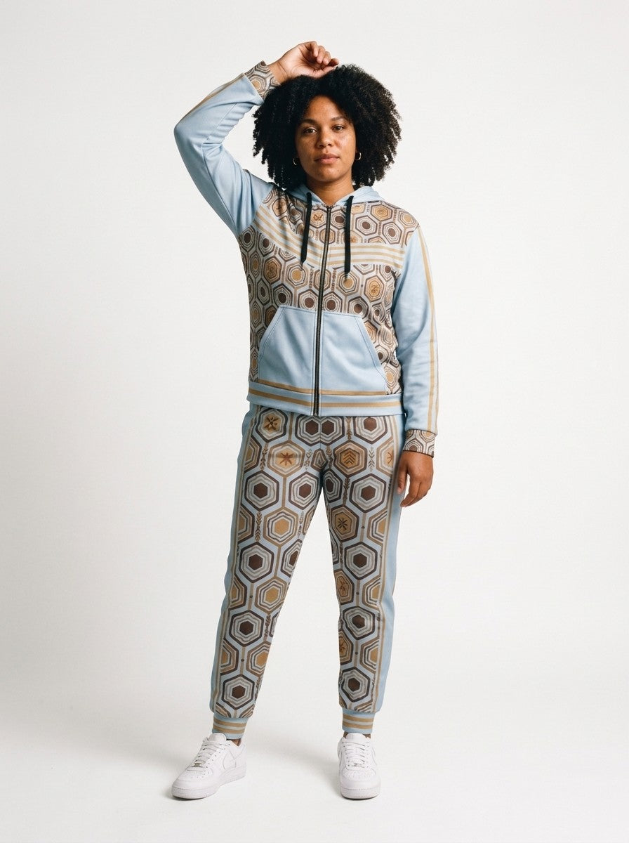 Women's tracksuit set in Igwe Blue: AnanseNova™ Zip Hoodie + Joggers on model, front view, bronze hexagon print with chevron chest stripes and full-leg jogger print | SunBorn