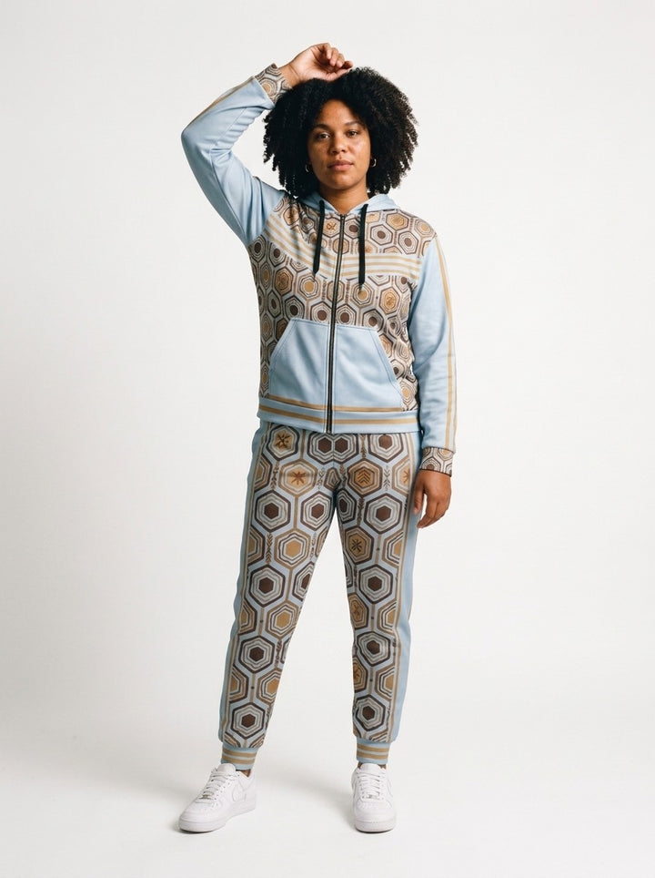 Women's tracksuit set in Igwe Blue: AnanseNova™ Zip Hoodie + Joggers on model, front view, bronze hexagon print with chevron chest stripes and full-leg jogger print | SunBorn