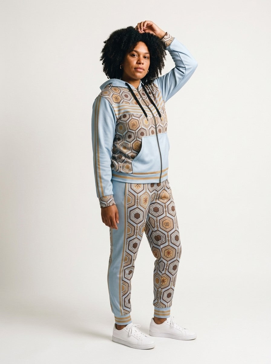 Three-quarter left view of the Igwe Blue AnanseNova™ women's Zip Hoodie + Joggers set on model, showing the jogger side panel and twin bronze pinstripes | SunBorn