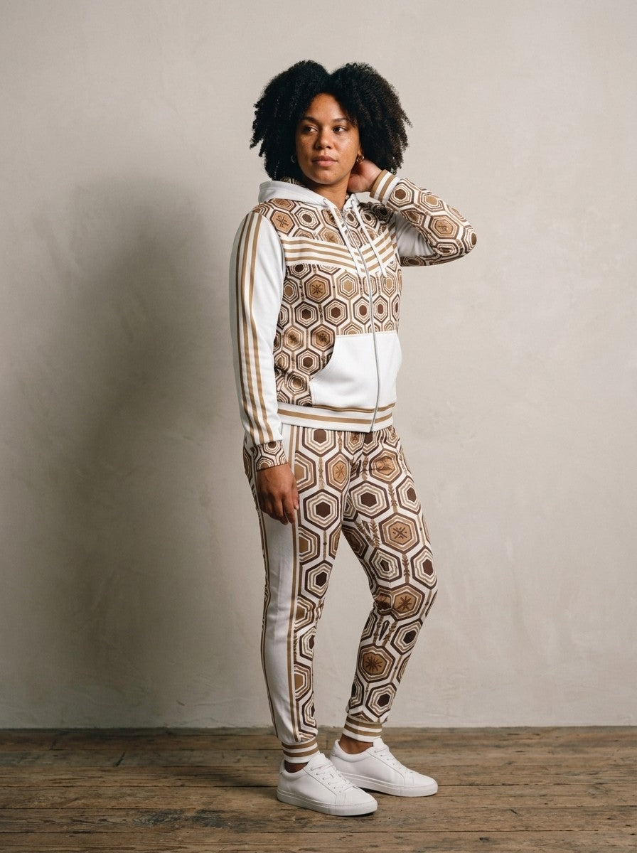 Three-quarter left view of the Ocha White AnanseNova™ women's Zip Hoodie + Joggers set on model, showing the jogger side panel and twin bronze pinstripes | SunBorn