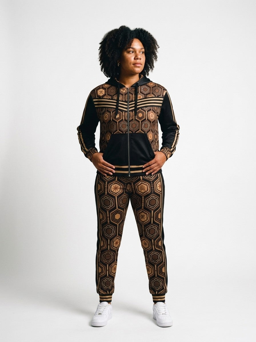 Front view of the AnanseNova™ women's Zip Hoodie + Joggers set in Oji Black on model, bronze hexagon print, black kangaroo pocket and side panels, bronze sleeve stripes | SunBorn