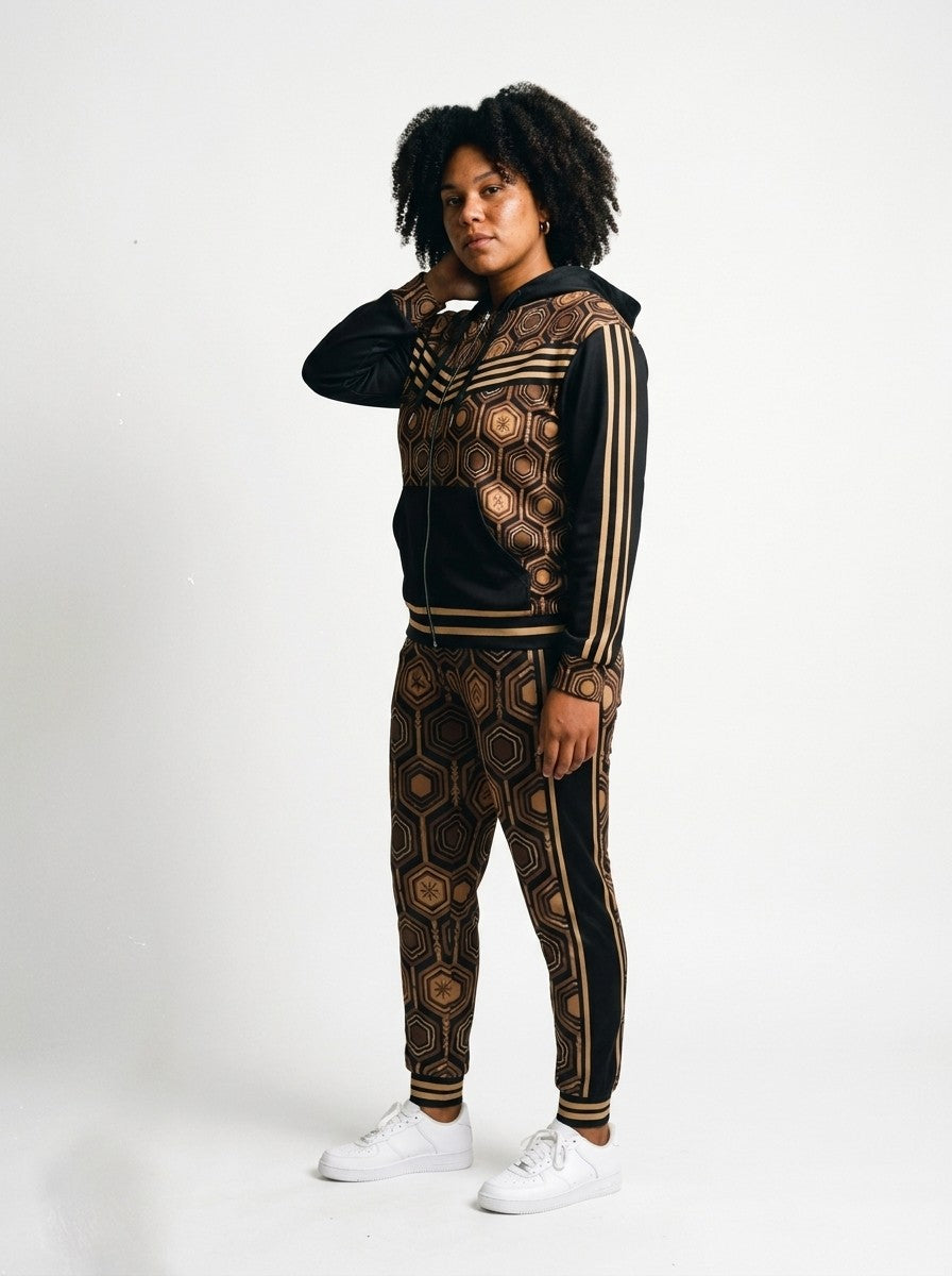 Three-quarter left view of the Oji Black AnanseNova™ women's Zip Hoodie + Joggers set on model, showing the jogger side panel and twin bronze pinstripes | SunBorn
