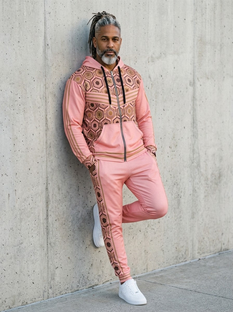 Man leaning against a concrete wall wearing the AnanseNova™ Zip Hoodie + Joggers Set in Eze Pink with white sneakers