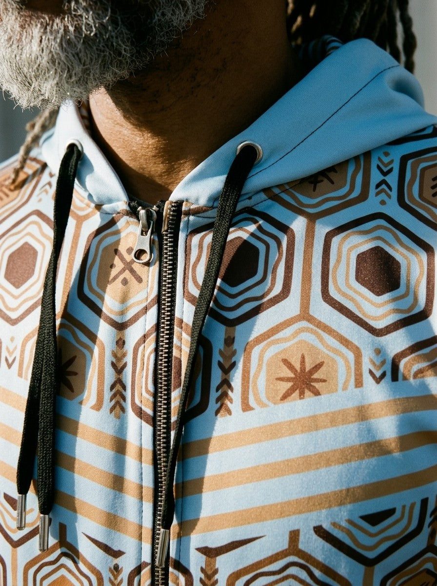 Close-up of the AnanseNova™ Zip Hoodie in Igwe Blue: drawcords, metal zip and the hexagon and stripe chest print