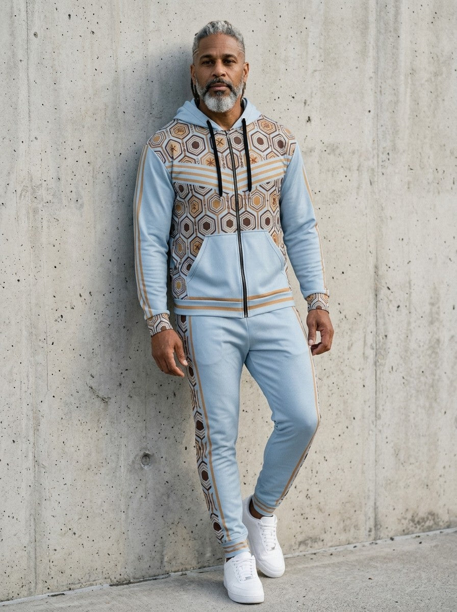 Man leaning against a concrete wall wearing the AnanseNova™ Zip Hoodie + Joggers Set in Igwe Blue with white sneakers