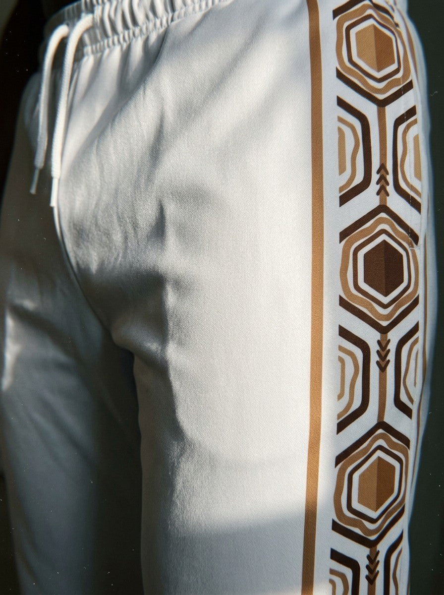 Close-up of the AnanseNova™ Joggers in Ocha White: drawcord waistband and the brown and gold hexagon side stripe