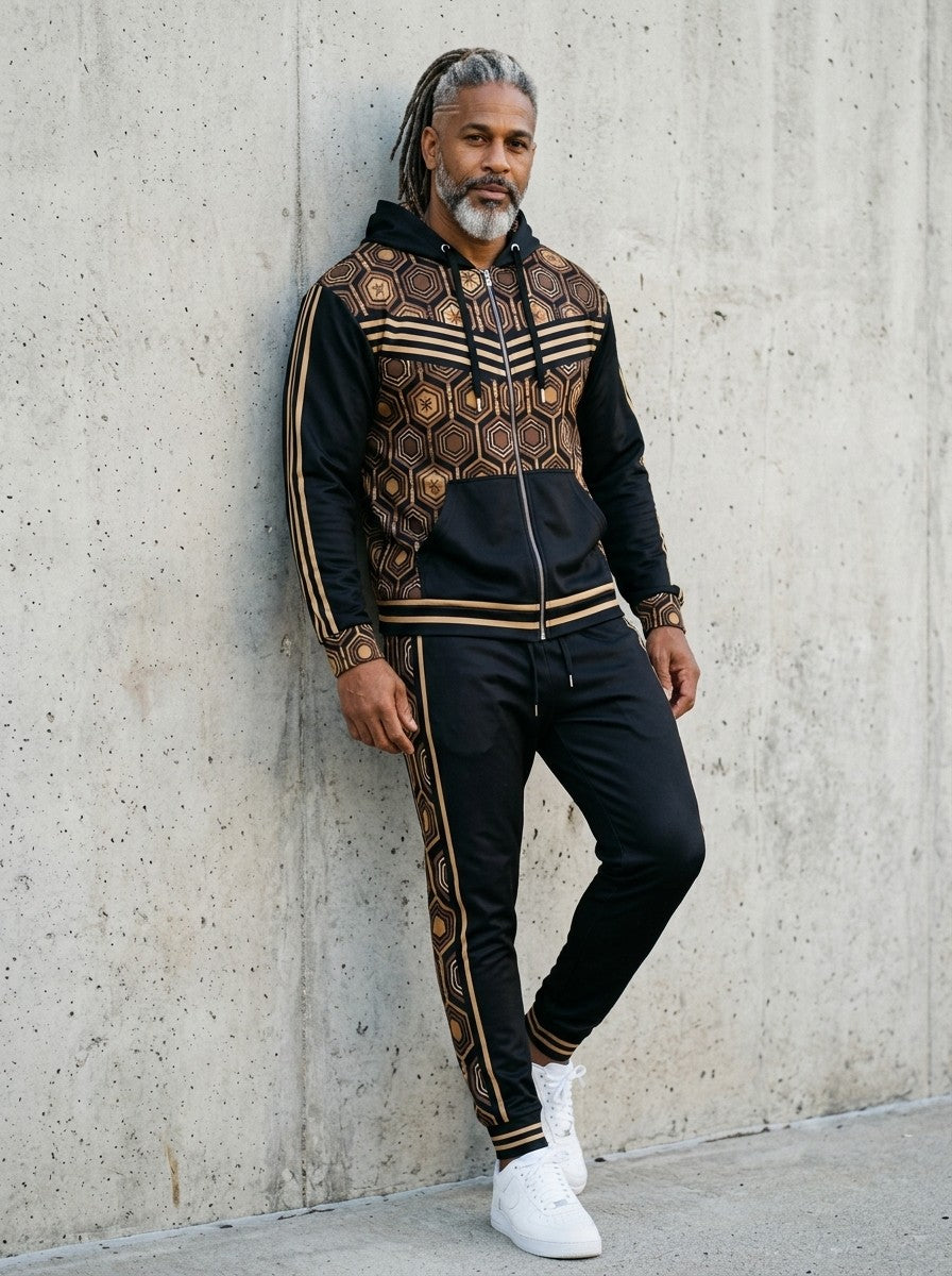 Man leaning against a concrete wall wearing the AnanseNova™ Zip Hoodie + Joggers Set in Oji Black with white sneakers