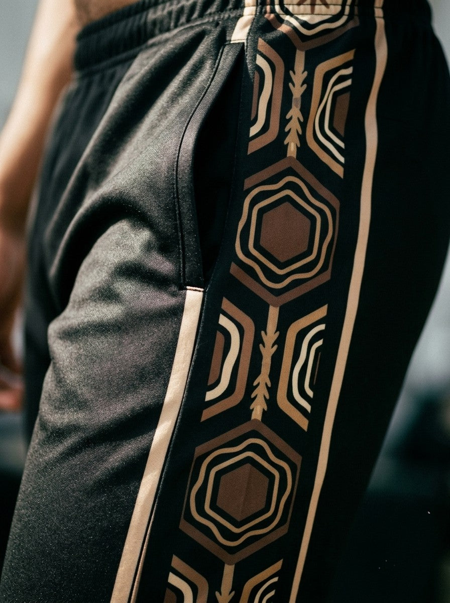Close-up of the AnanseNova™ Joggers in Oji Black: side pocket and the brown and gold hexagon side stripe
