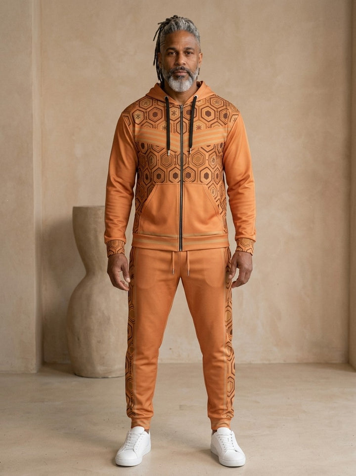 AnanseNova™ Zip Hoodie + Joggers Set in Sango Orange, front view on model: orange zip hoodie with brown and gold hexagon print panels and gold sleeve stripes, matching orange joggers with hex side stripes