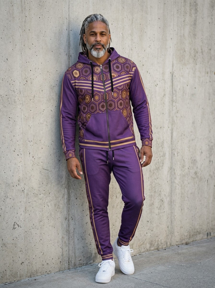 Man leaning against a concrete wall wearing the AnanseNova™ Zip Hoodie + Joggers Set in Ugo Purple with white sneakers