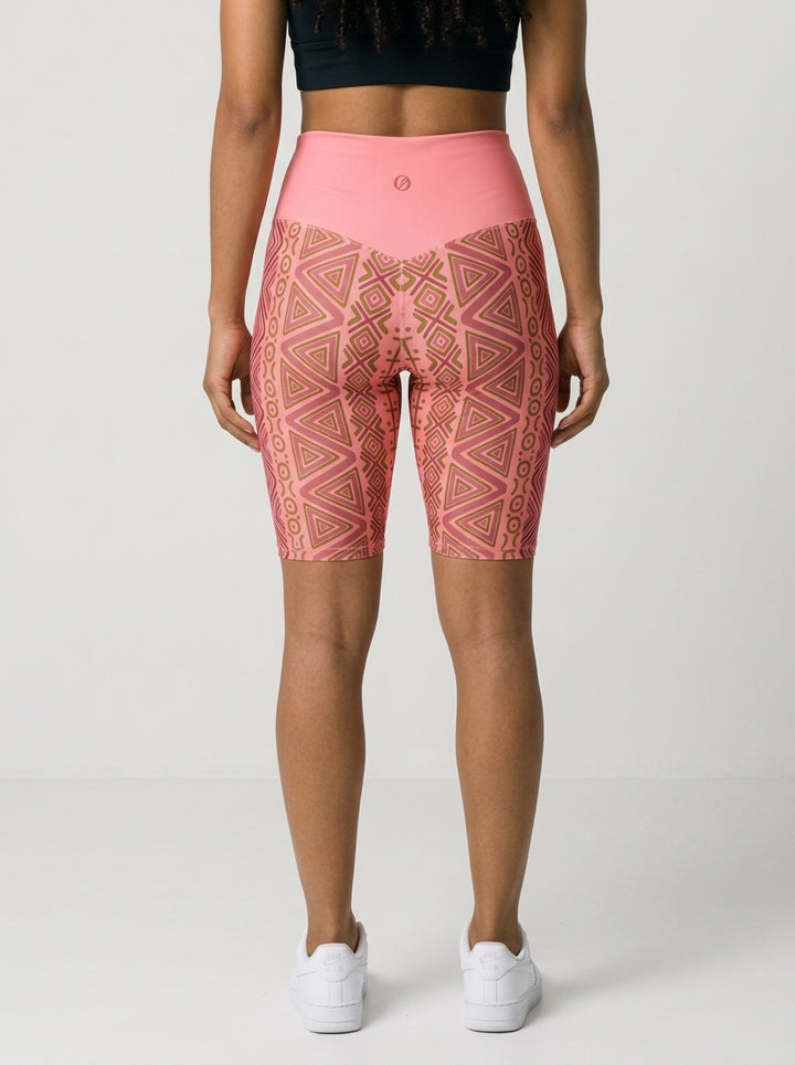 Back view of SunBorn N'Donso™ Biker Shorts in Adaeze Pink on model: V-back waistband with the SunBorn mark and mirrored zigzag print