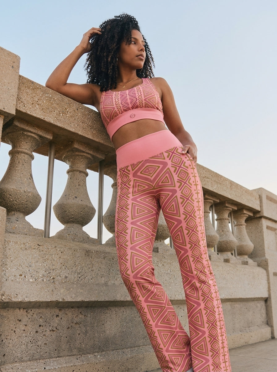 Woman leaning on a stone balustrade in the N'Donso™ Bra + Flare Leggings Set in Adaeze Pink, SunBorn AsaseFlex™ activewear