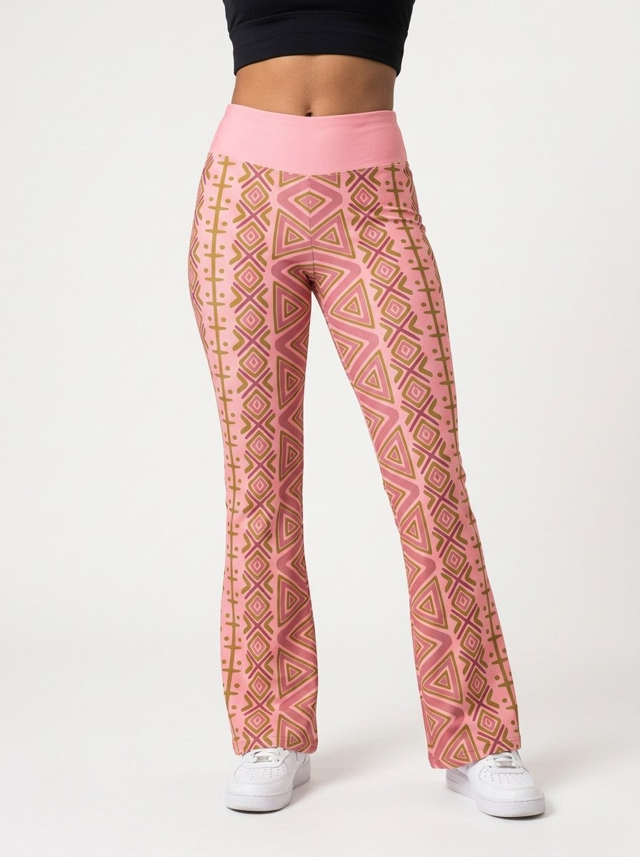 Woman wearing SunBorn N'Donso™ Flare Leggings in Adaeze Pink, front view: high-rise solid pink waistband and Hunter's Road print to a flared hem