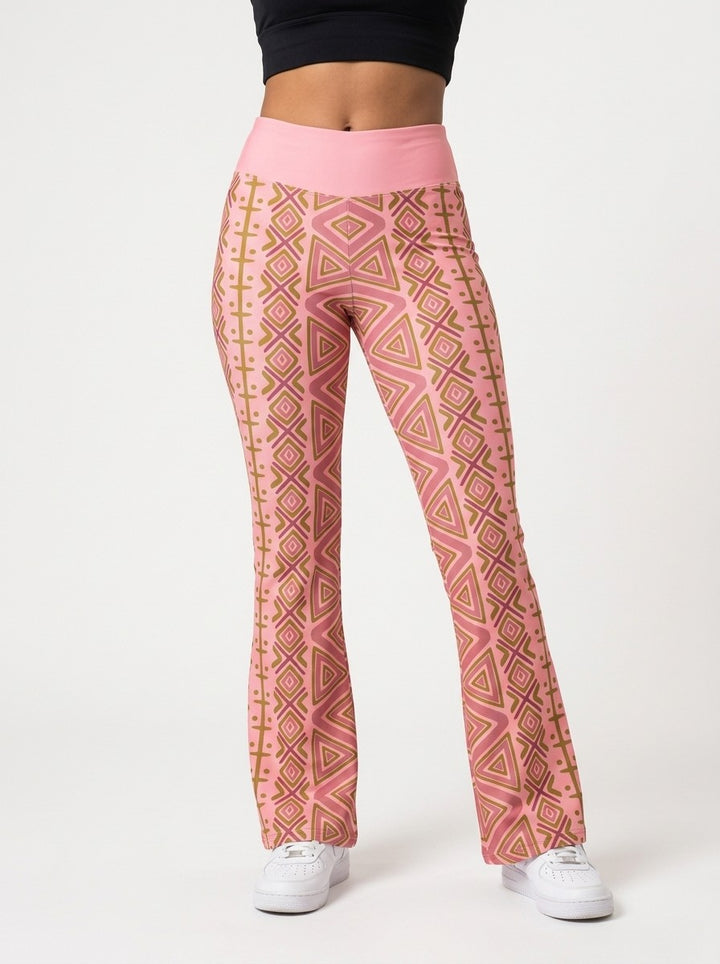 Woman wearing SunBorn N'Donso™ Flare Leggings in Adaeze Pink, front view: high-rise solid pink waistband and Hunter's Road print to a flared hem